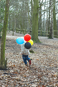 男孩把一堆气球带到户外图片