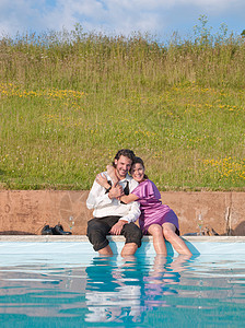 青年夫妇坐在游泳池旁拥抱图片