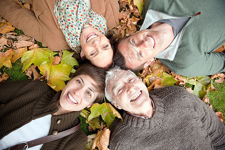 一家人躺在公园的秋叶里图片