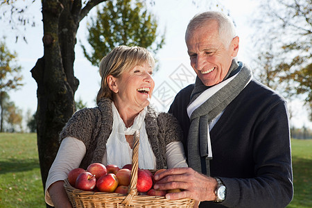 老年养生户外老年夫妇手持苹果背景