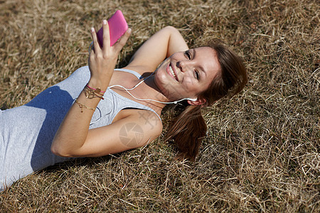 在草地上拿着手机的女人图片