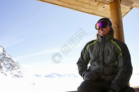 在滑雪小屋阳台上放松的男人图片
