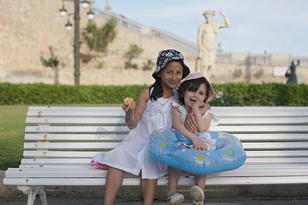 两个年轻女孩坐在长椅上图片