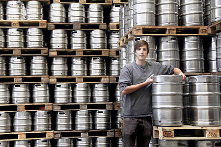 啤酒厂靠着啤酒桶的工人图片
