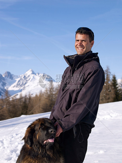 在雪山上带着狗的男人图片