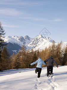 一对在雪中跑向山的夫妇图片