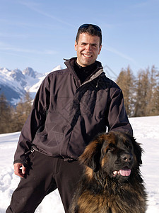 在雪山上带着狗的男人图片