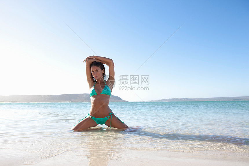 女人蹲在海滩的水里图片
