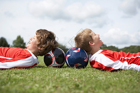 两个男孩头枕着球休息图片