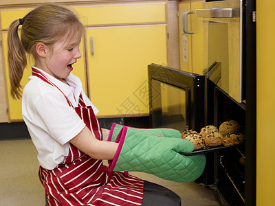 一个女孩从烤箱里拿面包背景图片
