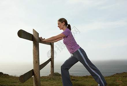一个女人在乡间篱笆上伸展图片