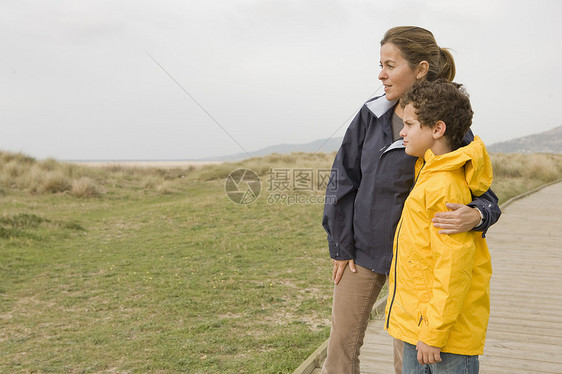 母亲抱着儿子在海滩木板路上图片