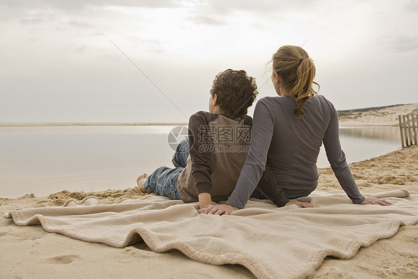 母亲和儿子坐在海滩上图片