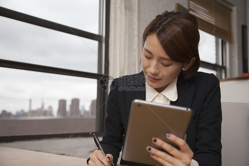 女商人拿着数字平板电脑和笔记图片