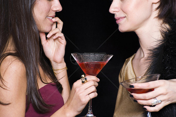 两个女人面对面地在夜总会里喝鸡尾酒图片