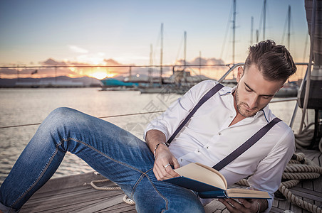 牛仔裤背景在意大利撒丁岛卡利亚里游艇上读书的年轻人背景