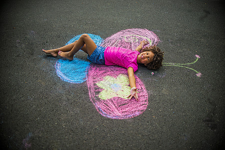 小女孩躺在粉笔蝴蝶翅膀之间的地板上高清图片