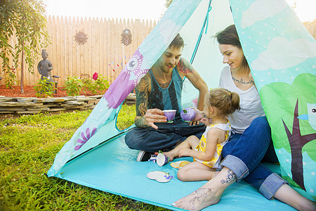 年轻夫妇和学步的女儿在帐篷里喝茶图片