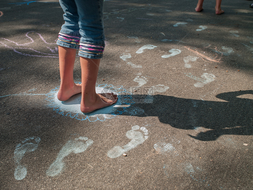 女孩赤脚在人行道上踩粉笔脚印