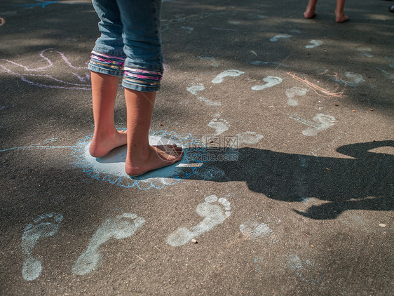 女孩赤脚在人行道上踩粉笔脚印图片