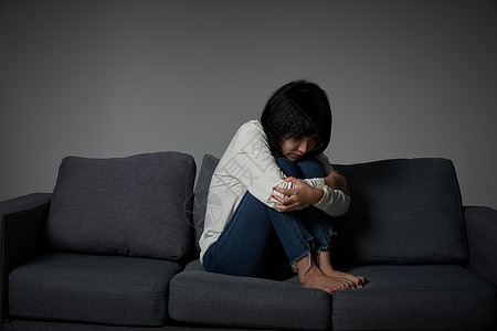 年轻女性坐在沙发上哭泣图片素材