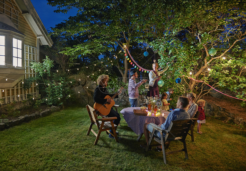 夜晚花园中举办家庭聚会的快乐一家人图片