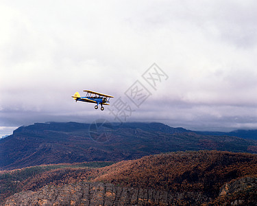 背景中有山脉的双翼飞机图片