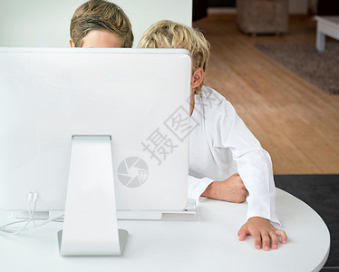 在电脑屏幕后面的男孩使用电脑高清图片素材