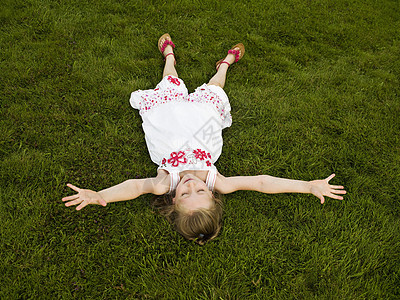 躺在草地上伸展双臂的女孩图片