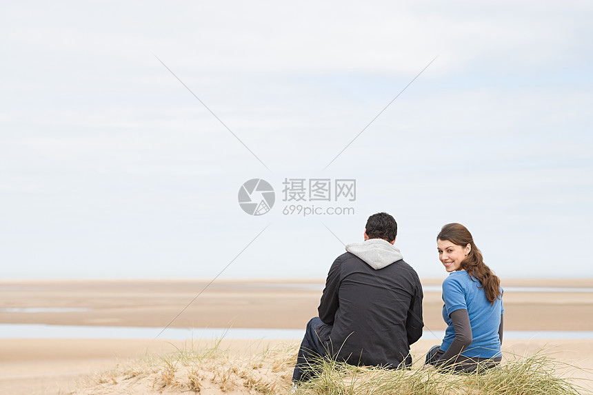 一对夫妇坐在空荡荡的海滩上图片