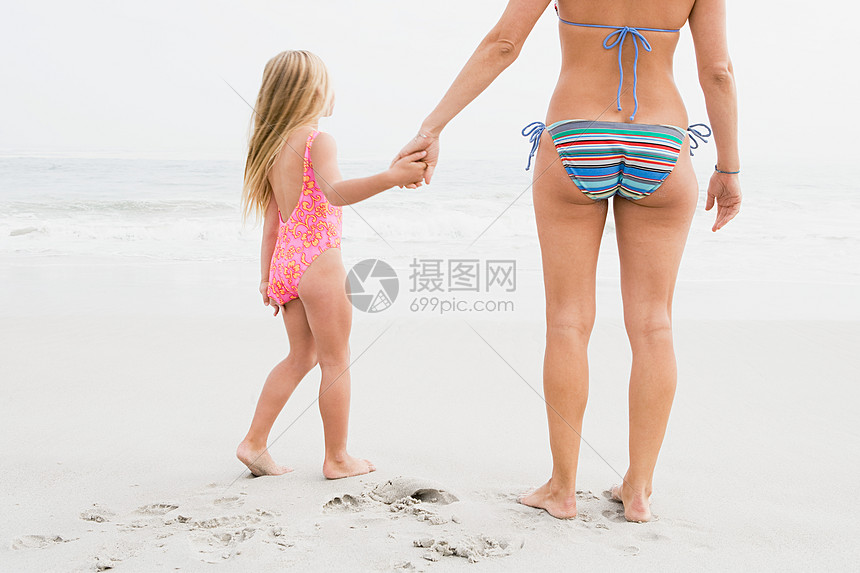 女孩和母亲手牵着手在海滩上图片