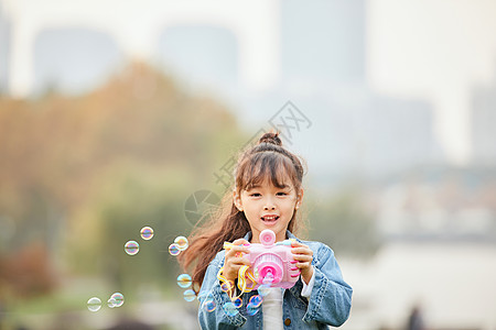小女孩草地上玩泡泡机背景