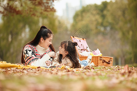 户外温馨母女趴在草地上看书背景