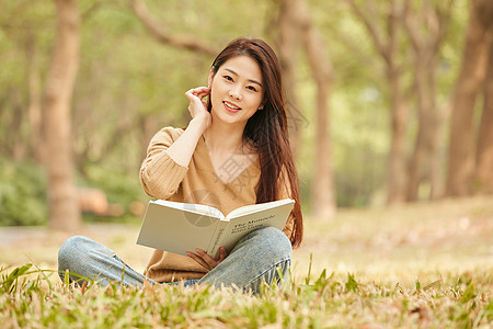 年轻女性坐在草地上看书图片