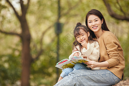 亲子温馨母女坐在树下读书背景