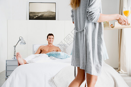 男人躺在床上，女人拿着托盘图片