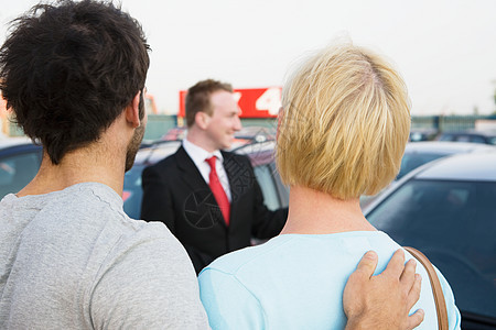 一对夫妇和一个汽车经销商的销售员在看车图片