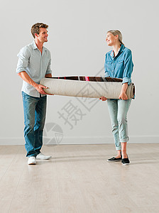 搬卷起的地毯的年轻夫妇图片