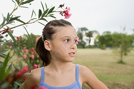 站在一棵开花的树旁的女孩图片