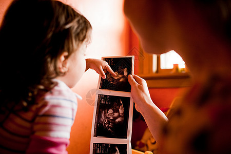 母亲和女儿看着婴儿的扫描照片图片