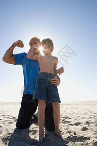 爷爷和儿子在海滩上弯曲二头肌图片