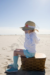 坐在沙滩上野餐篮上的女孩图片