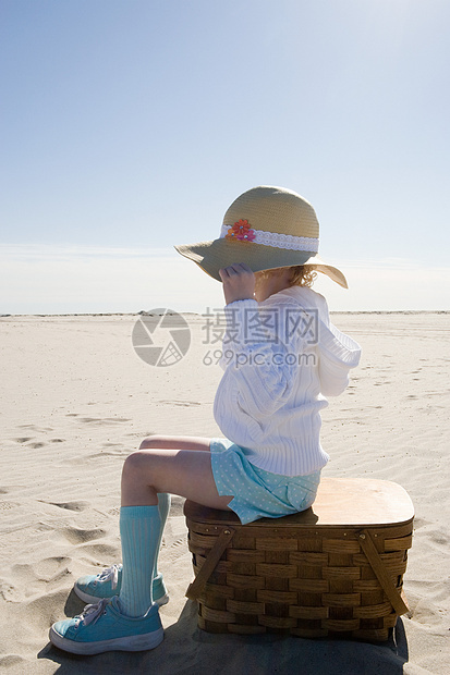 坐在沙滩上野餐篮上的女孩图片