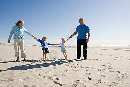 祖父母和孙子孙女手牵着手，在海滩上散步背景图片
