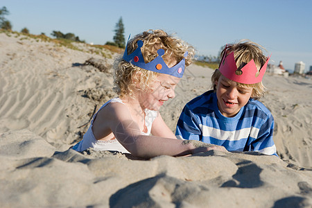 沙滩男孩孩子们戴着纸冠在海滩上玩耍背景