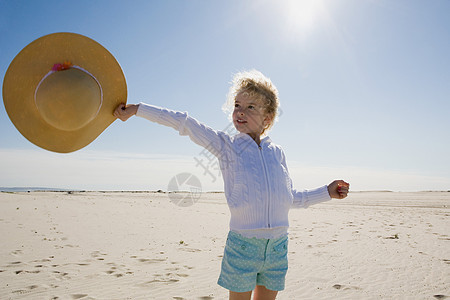 在海滩上举草帽的女孩图片