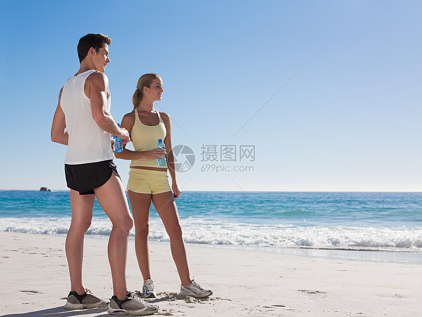 海滩上带着瓶装水的年轻夫妇图片