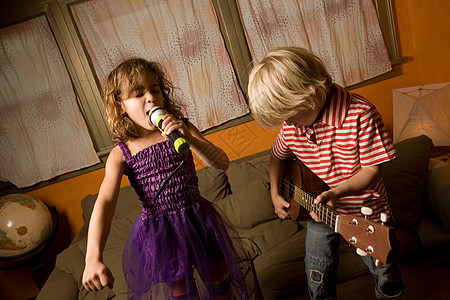 孩子吉他女孩用麦克风唱歌，男孩弹吉他背景