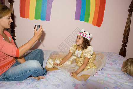 母亲给穿公主服装的女儿拍照图片
