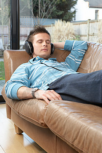 在沙发上听音乐的男人图片